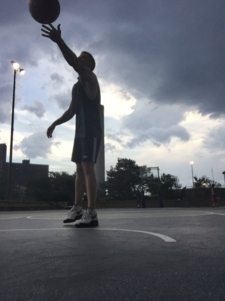 carl charles shooting a basketball on a basketbal court on a cloudy day